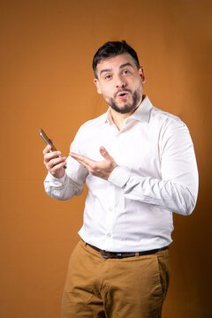 Hombre con expresi&oacute;n de estar sorprendido mostrando su celular. Concepto de comunicaciones y atenci&oacute;n