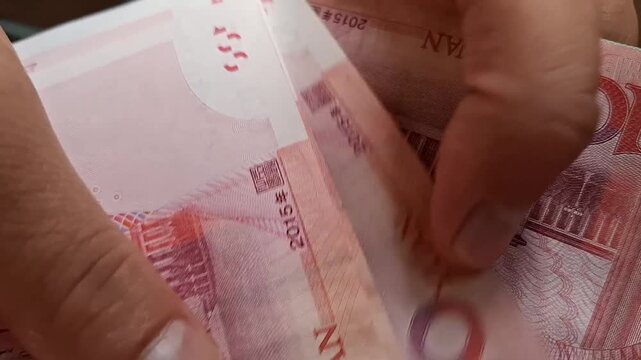 Person counts one hundred Chinese yuan banknotes with hands in a close-up shot. chinese currency exchange, cash payment transaction, asian financial economy.