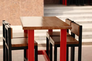 Fototapete Gastronomie Empty outdoor street cafe furniture setup with industrial loft style wooden tables and high metal bar stools.  © Aigul Sabirova