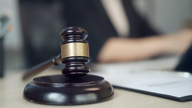 Close-up of a judge's gavel placed on a desk with legal documents in the background. Suitable for justice, law, legal consultation, court proceedings, attorney services, contracts, compliance, and jud
