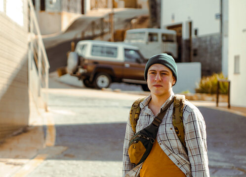 A man is wallking in a town on a sunny day, a tourist enjoys his leasure time walking on the streets of a city.