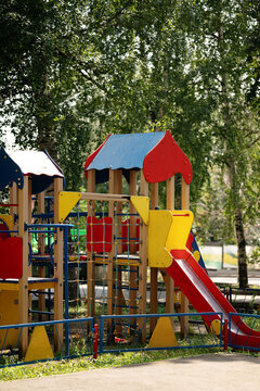 Colorful empty children playground with slides and climbing equipment in a green residential courtyard. Outdoor recreation, childhood, neighborhood amenities and family friendly urban environment.