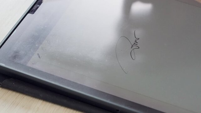 Close-up of a hand signing an electronic document on a digital tablet using a stylus pen. Ideal for e-signature, paperless workflow, business agreement, contract approval, legal documentation, and mod