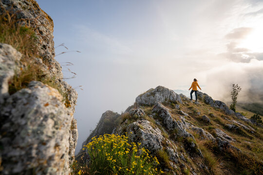 A determined hiker stands on a mountain peak to celebrate reaching her summit goal