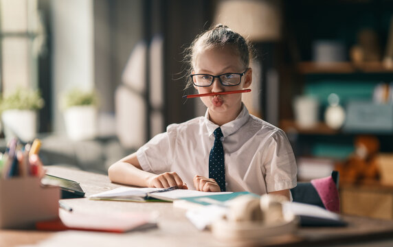 Cheerful Schoolgirl Making Funny Face While Studying at Desk