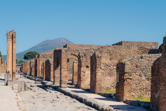 Tourists walking through the archaeological ruins of Pompeii with Mount Vesuvius in the background