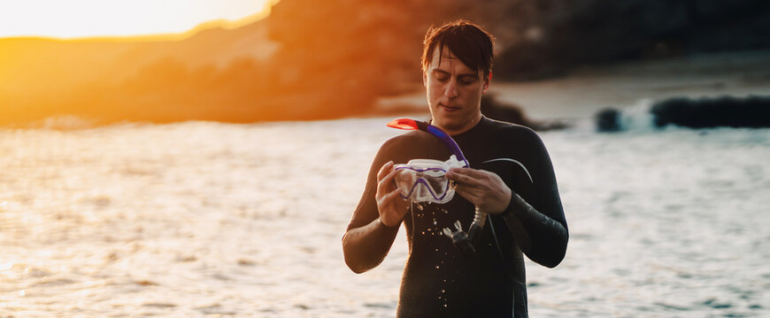 A man is preparing for diving in the ocean at sunset.
