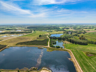 Expansive drone shot of open fields and a distant lake in the Barkoczyn area, capturing the wide horizons and peaceful rhythm of rural Poland. © Lukasz
