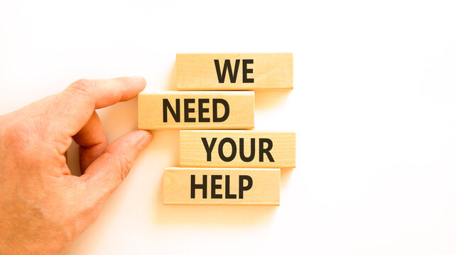 We need your help words symbol. Concept words We need your help on beautiful wooden blocks. Beautiful white background. Businessman hand. Business support we need your help concept. Copy space.