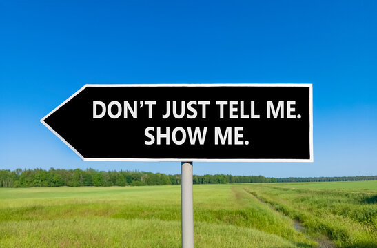Tell or show symbol. Concept words Do not just tell me, show me beautiful black road sign. Beautiful blue sky green field background. Business tell or show concept. Copy space.