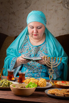A Jewish woman prays from the siddur at a table set out