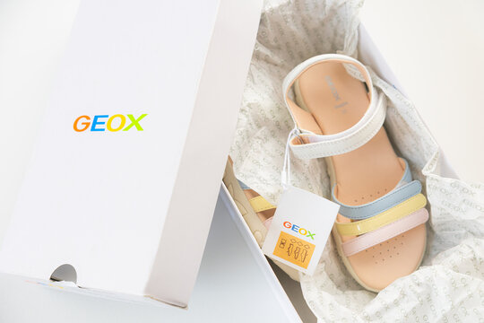 Unboxing new Geox girls sandals with multicolored pastel straps in branded white box over white background