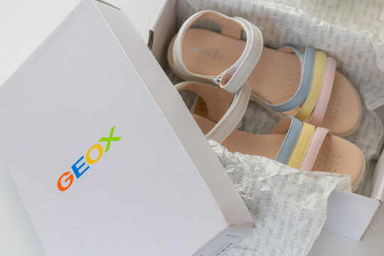 Unboxing new Geox girls sandals with multicolored pastel straps in branded white box over white background