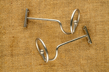 Spiral metal curtain rod in satin nickel color on jute fabric, close-up. © Oleksandr
