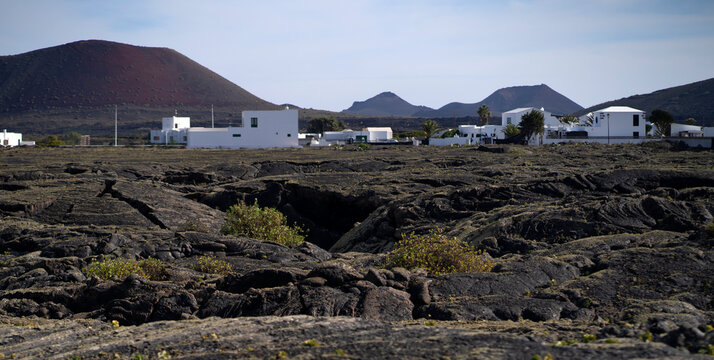 White houses among black lava formations, volcanic earch, mountains and volcanoes of Lanzarote island.