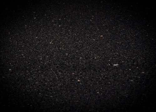 An asphalt road in a dark shades closeup texture.