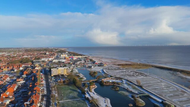 Aerial view of a coastal town with red rooftops and icy shores. rural landscape, Wainfleet, Village, Skegness in morning sunrise wintertime.