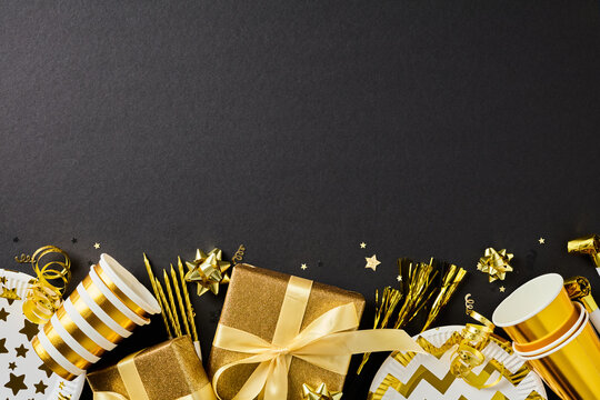 Golden party supplies and gift border on dark bottom background