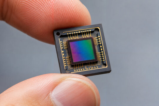 Macro close up of fingers holding a digital camera image sensor