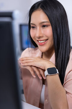 Woman computer smartwatch office smile portrait desk technology Asian woman smiling computer modern office, wearing smartwatch and pink shirt while working desk with cheerful expression Vertical