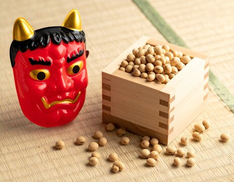 Japanese Setsubun still life with roasted soybeans in a wooden masu box and a red demon mask