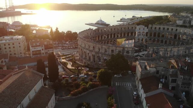 Golden sunset illuminating the historic Roman Arena in Pula with the Adriatic coastline in the background.