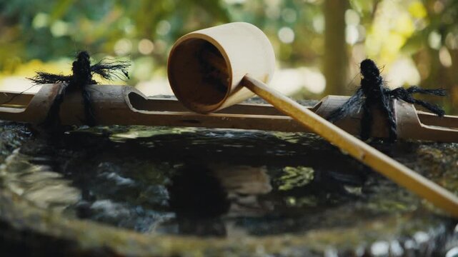Japanese bamboo water ladle dripping into a stone basin