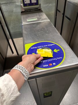 Passenger validates a yellow Navegante travel card at Lisboa Oriente train station by holding it over a contactless reader on the stainless steel metro entrance gate, Lisbon, Portugal, 2 April 2026