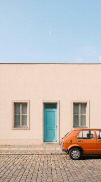 Retro Orange Car by a Pastel Building