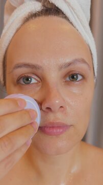 Woman applying a microcurrent facial device to her cheek, engaging in professional anti aging skincare for healthy, youthful, and radiant skin rejuvenation in a relaxing home spa setting
