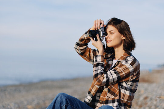 Photography, photographer, camera, woman, beach, outdoor photographer on the windy coast wearing a plaid shirt, capturing a calm seaside moment with the camera lifted, casual portrait and lifestyle