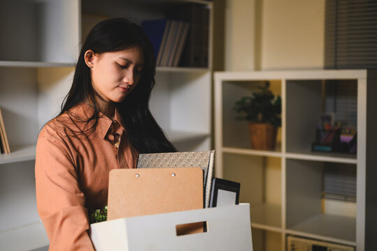 Asian Businesswoman Packing Personal Belongings in Box While Resigning from Office Job