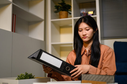 Young Asian Businesswoman Packing Office Belongings into Box After Resignation, Holding File Binder