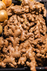 Fototapeta premium Fresh ginger roots displayed in supermarket produce section with organic spice ingredient and healthy food concept