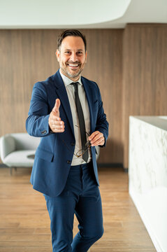 Smiling male executive offering a friendly handshake, symbolizing greeting, agreement, and partnership within a contemporary business environment