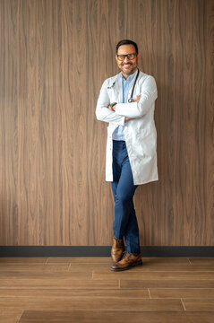 Medical professional standing confidently, smiling, wearing a lab coat and stethoscope, representing healthcare, wellness, and medical expertise in a clinic environment