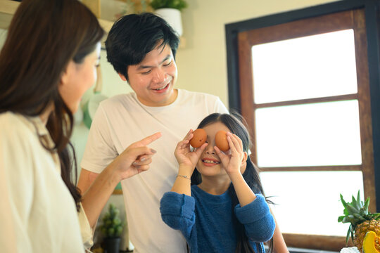 Happy Family Playing with Eggs in Kitchen, Domestic Life with Playful Child and Smiling Parents
