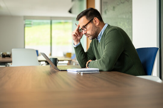 Businessman solving problems and experiencing professional stress in an office, working intensely on digital solutions, feeling exhausted and pressured