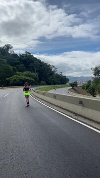 Young woman running on mountain highway road, rear view