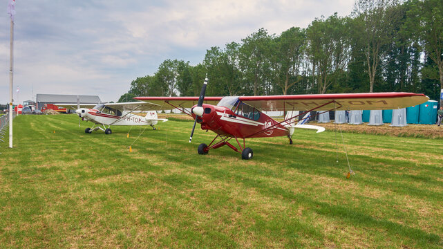 Piper PA-18 Super Cubs at Oostwold Airshow aviation event and general aviation aircraft in the Netherlands Two classic propeller airplanes are parked on a green grass field