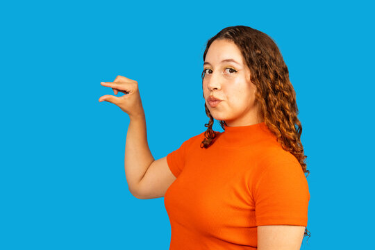 Woman showing small size gesture on blue background