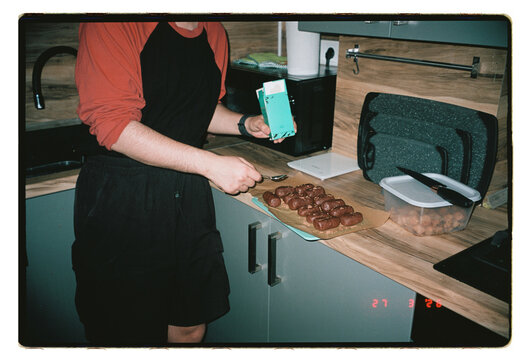 A man arranges homemade chocolate treats on a kitchen counter