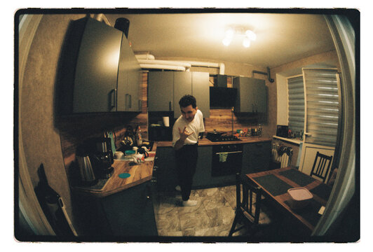 A man mid-gesture in a compact apartment kitchen