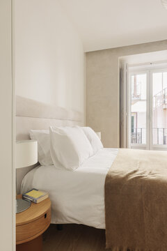 Bedroom with round oak nightstand and cylindrical lamp