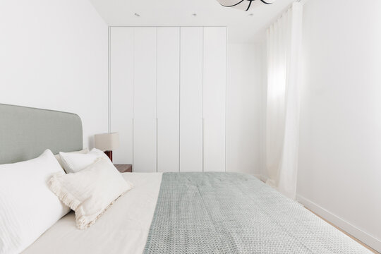 White built-in wardrobes and sage green bed in bedroom