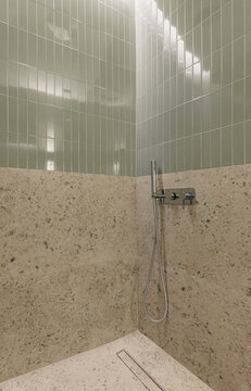 Walk-in shower with sage green tiles and terrazzo walls