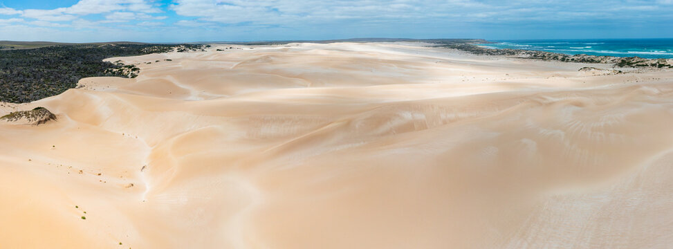 Shadow patterns on coastal sand dunes stretching off to the horizon