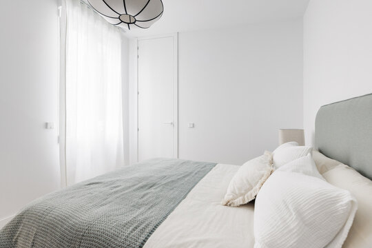 Bright bedroom with sheer curtains and sage green bedding