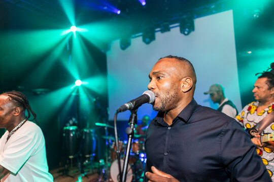 Male singer performing live music on stage with band