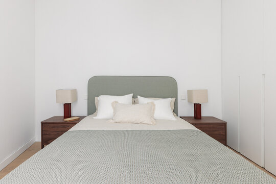Symmetric bedroom with sage green headboard and matching lamps